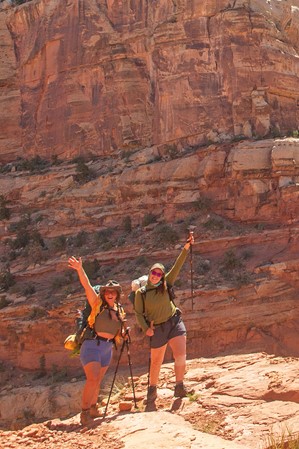 Two female hikers smile and pose on a trail in Capitol Reef National Park.