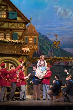 Performers on a stage with European-style house facades used as decorative props.