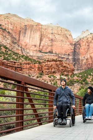 Two people in wheelchairs explore an accessible trail in Zion National Park.